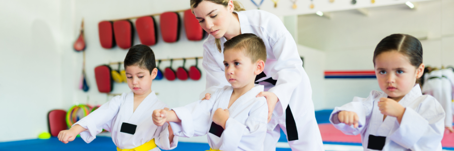 Grupa dzieci ćwiczących karate pod okiem instruktora.