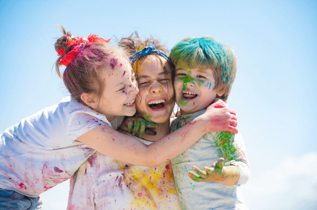 Opiekunka tuli roześmiane, brudne od kolorowego proszku dzieci podczas rekrutacji.