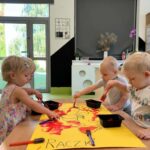 Dzieci wspólnie malują obrazek raczka w żłobkowej sali