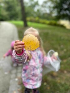 Dziecko trzyma w dłoni znaleziony jesienią liść.