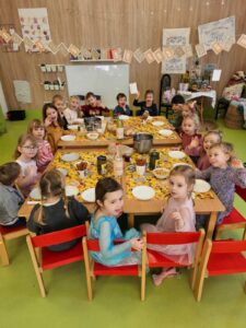 Grupa uśmiechniętych przedszkolaków siedzi przy stoliku