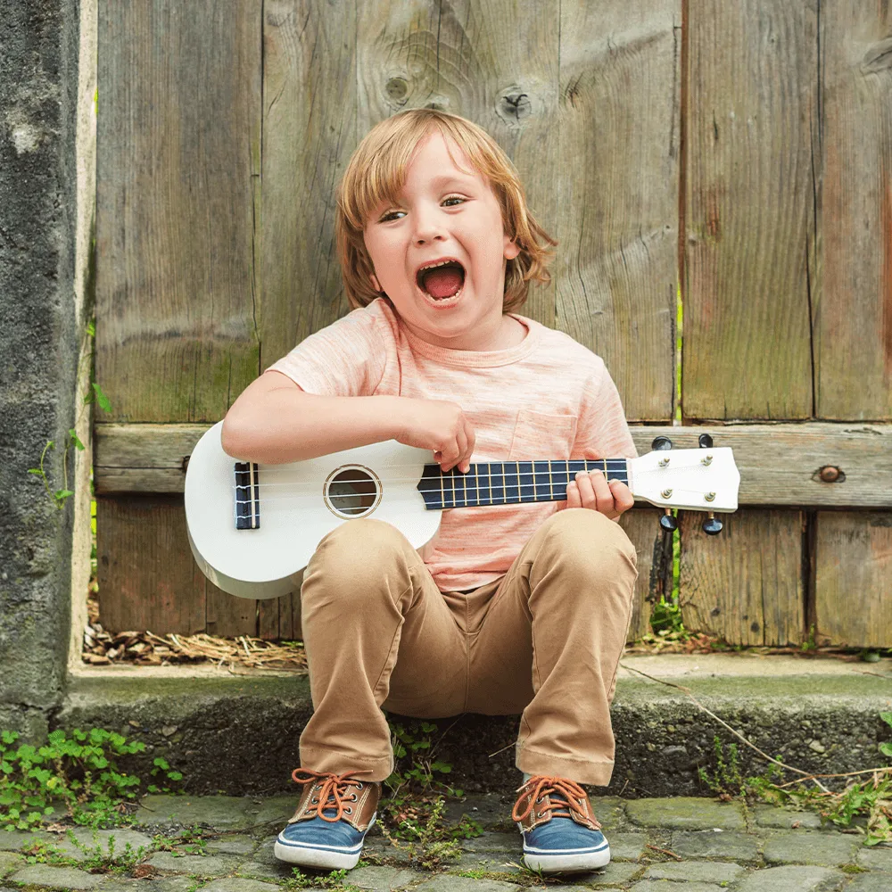 Chłopiec gra na gitarze podczas zajęć muzycznych na zewnątrz