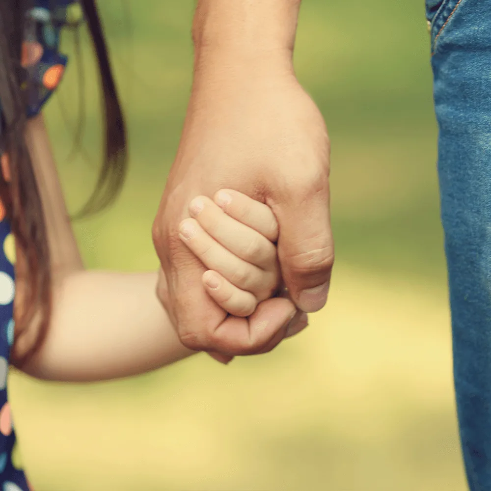 Dziecko trzyma za rękę opiekuna psychologicznego