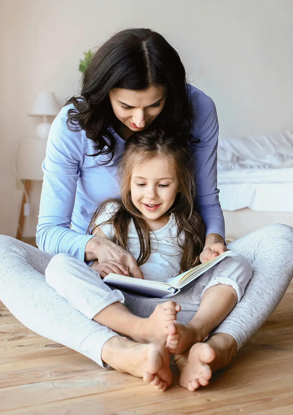 Mama siedzi z dziewczynką po turecku i wspólnie przeglądają książkę