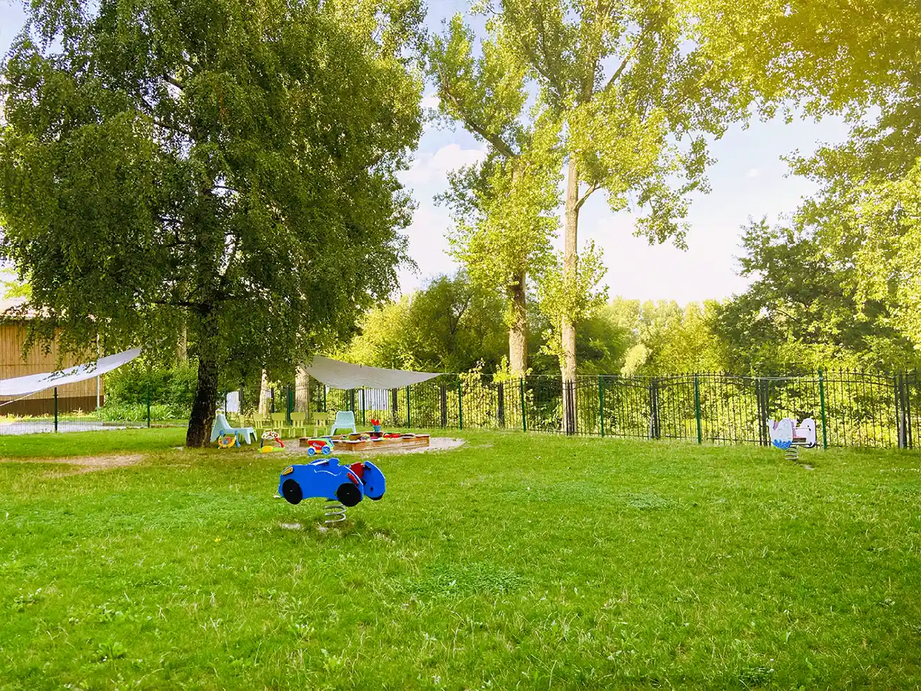 Zielone podwórko z piaskownicą przed budynkiem Bajkowa Przystań